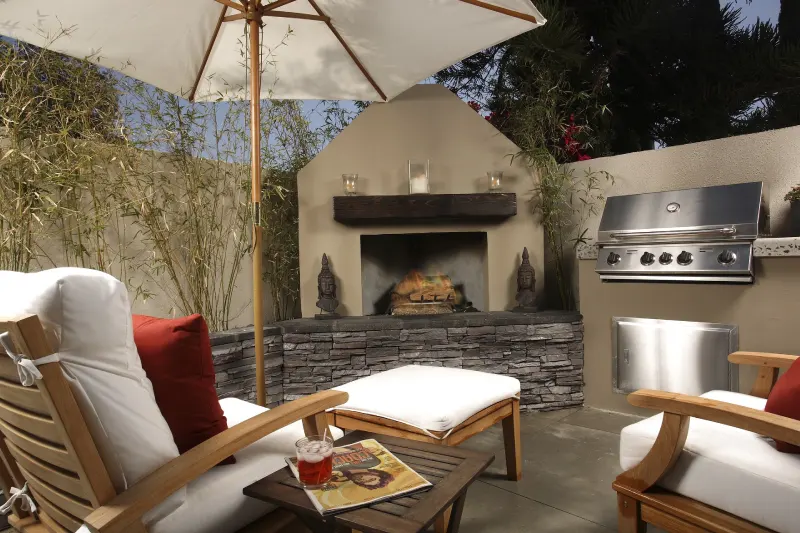 A patio with an outdoor fireplace and grill.